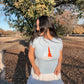 Woman wearing a light blue t-shirt with a sailboat design outdoors.